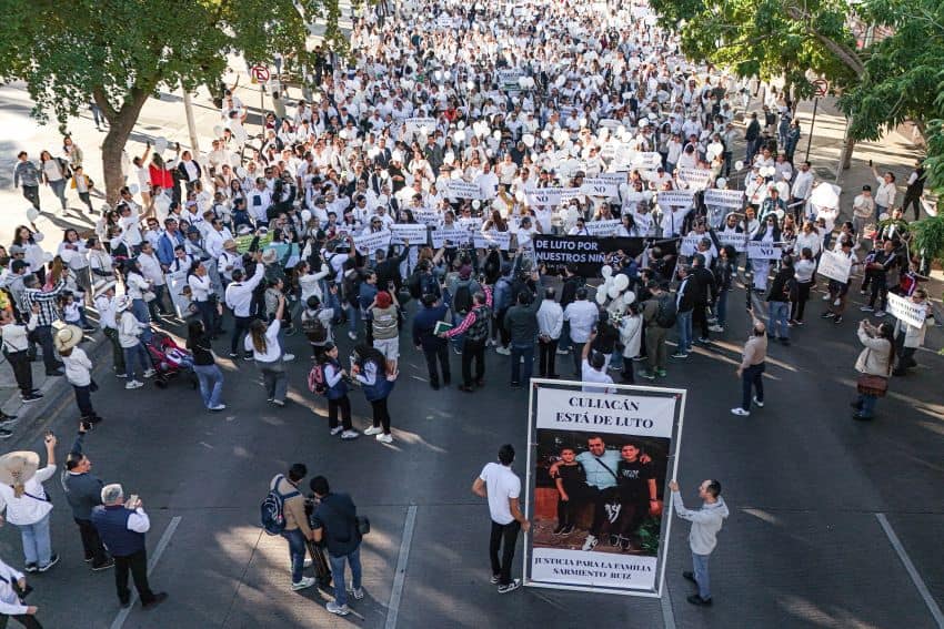 Hundreds of protesters in white can be seen gathered around a banner reading