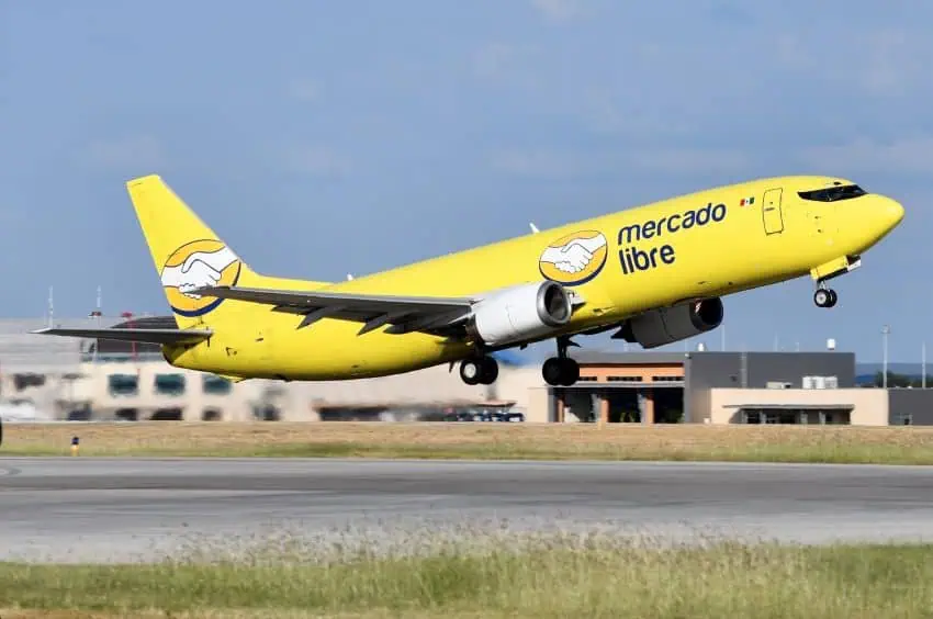 A yellow Mercado Libre airplane takes off from a runway