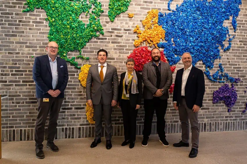 Leaders from LEGO and Nuevo León pose in front of a mural of a world map made of LEGOS