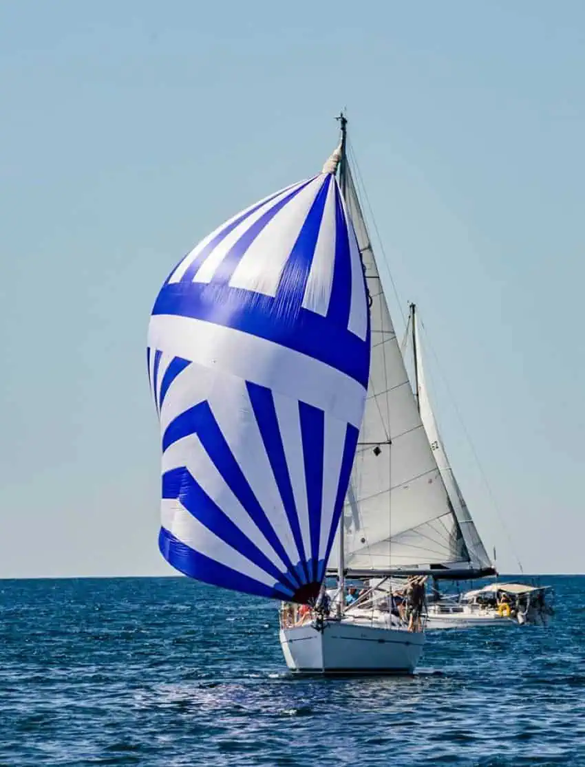 Un velero con velas de rayas azules y blancas en el océano