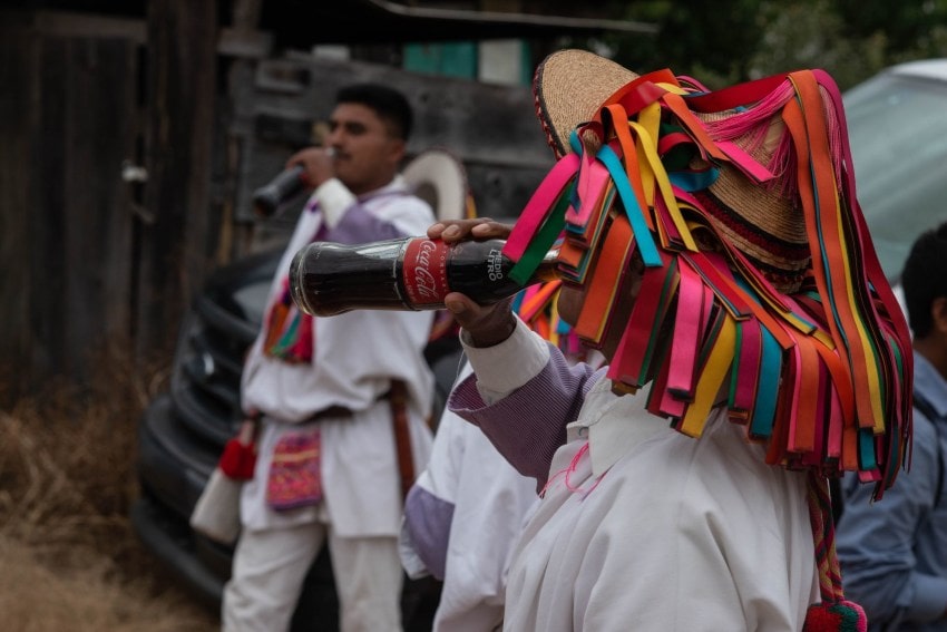 Los residentes indígenas de tzotzil con ropa tradicional se encuentran en las calles de San Cristóbal de Las Casas, Chiapas, beber botellas de coca cola.