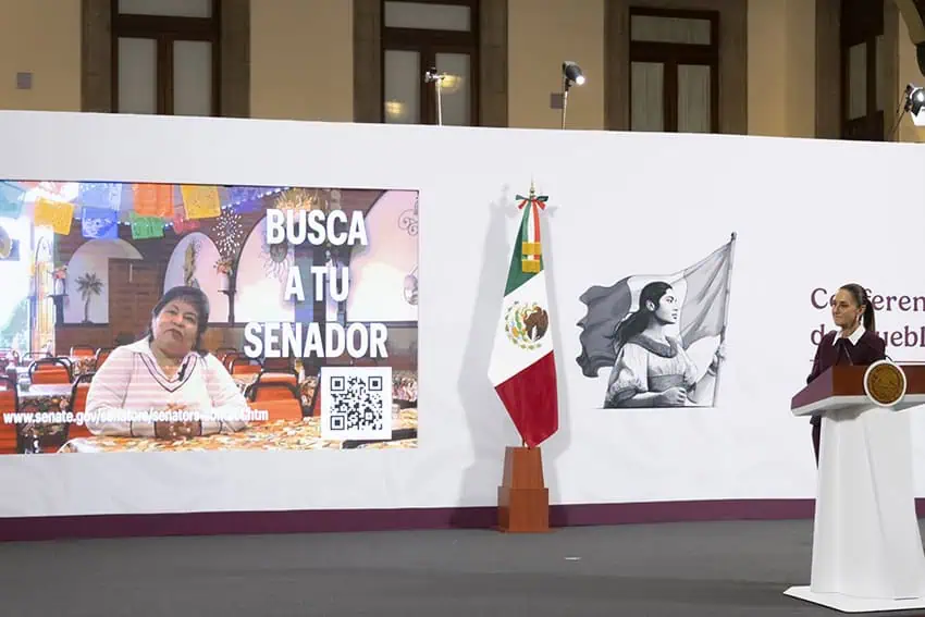 Sheinbaum al lado de una pantalla que lee "Contacta a tu senador" en su conferencia de prensa matutina