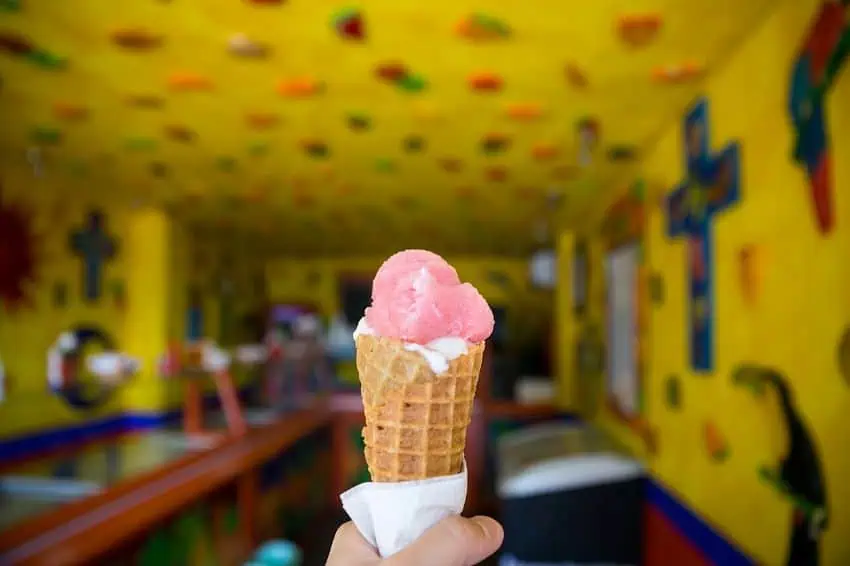 Helado rosa en cono sujeto a mano