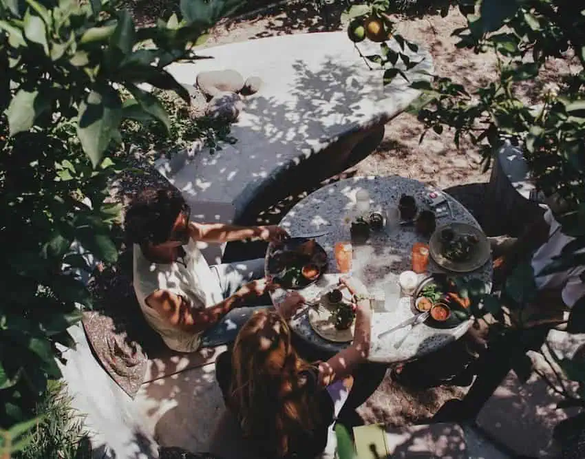 Una pareja come y bebe en un restaurante de jardín.
