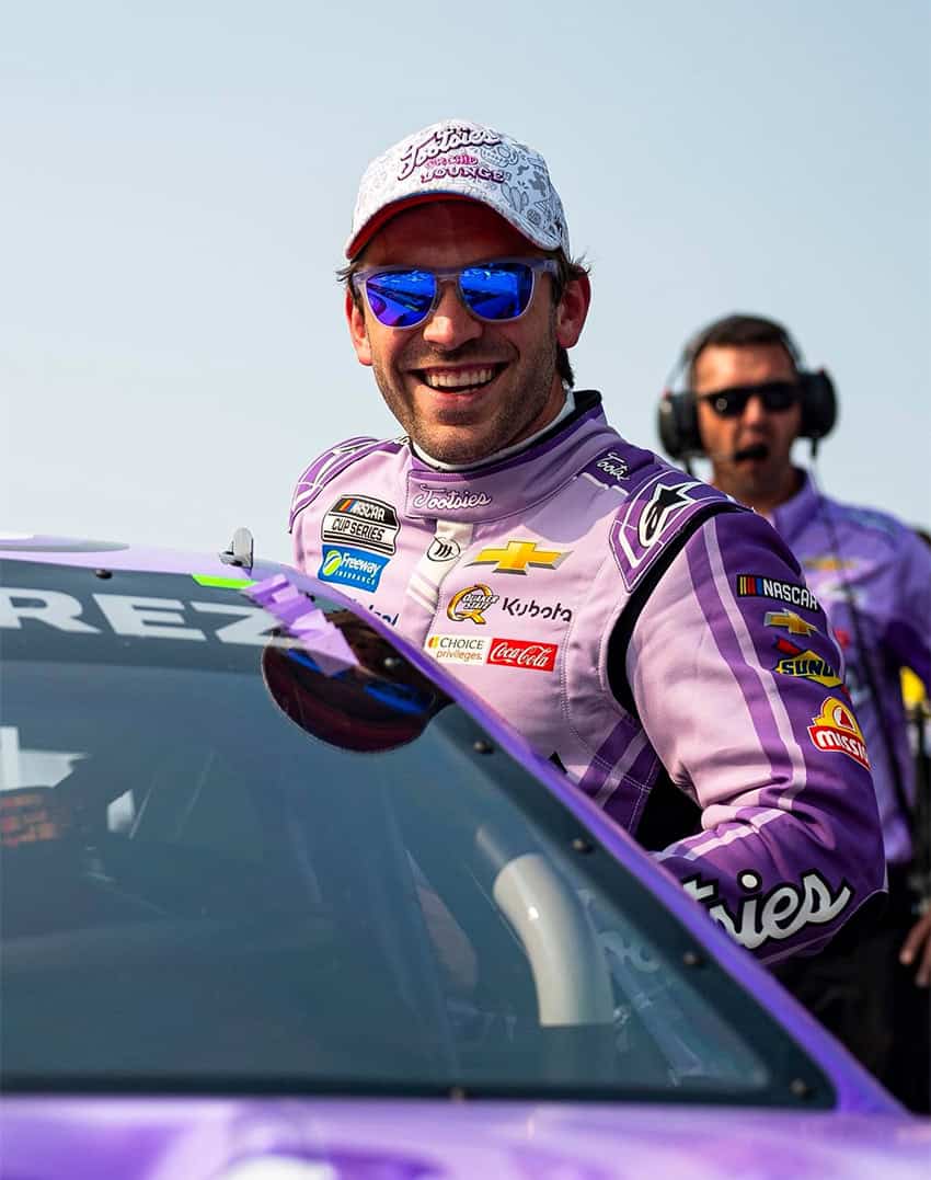 Un corredor de NASCAR cuelga de su auto para una foto