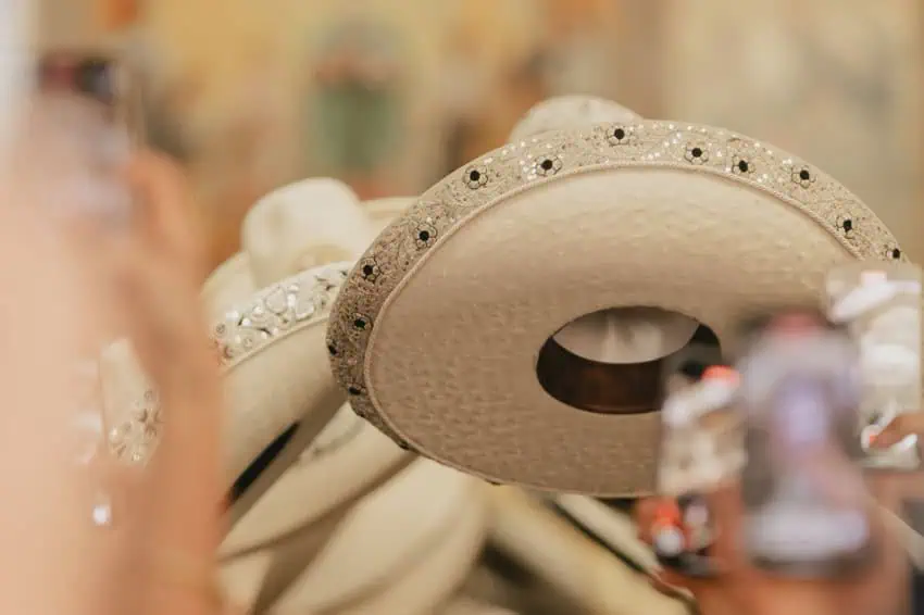 Close-up of a line of white leather Mexican sombreros, all decorated similiarly on the rims with beads and embroidery.