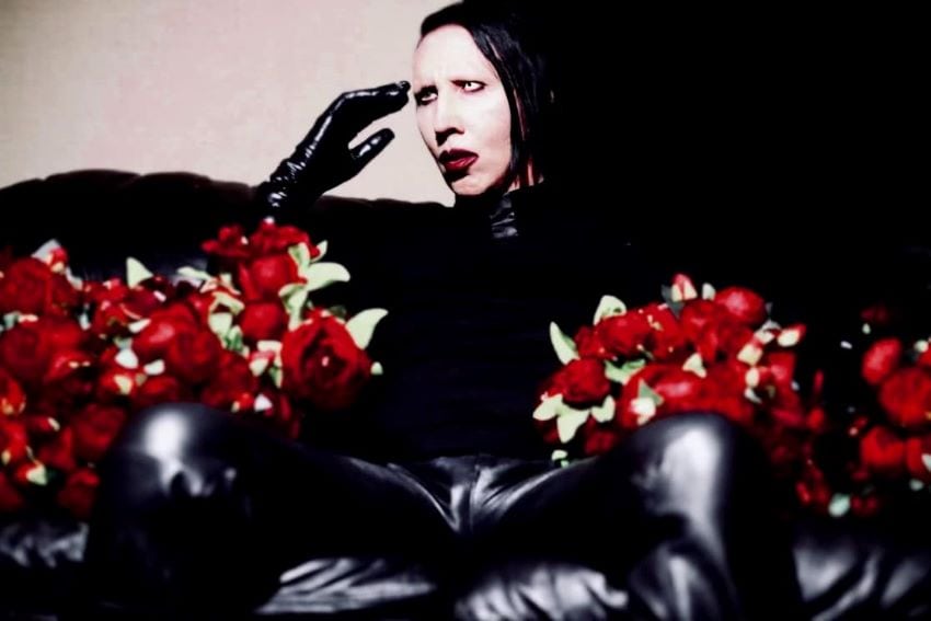 Man with face makeup holding flowers
