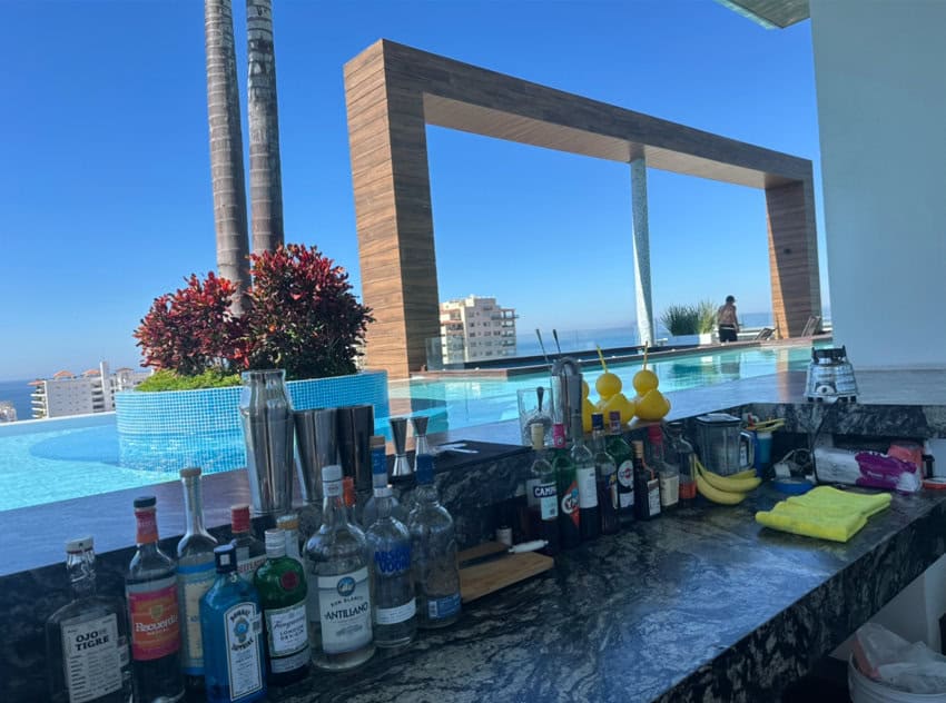Un bar con botellas de licor y licuadoras en un bar en la azotea rodeó la piscina Bya.