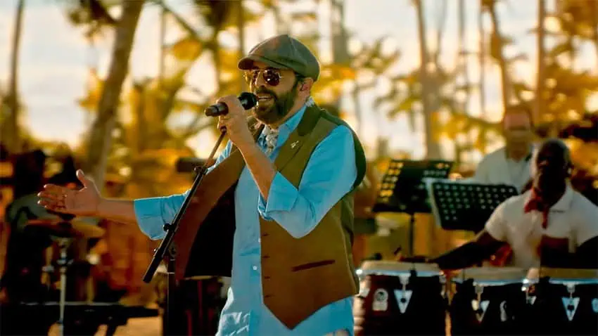 Juan Luis Guerra canta con una banda al atardecer frente a las palmeras