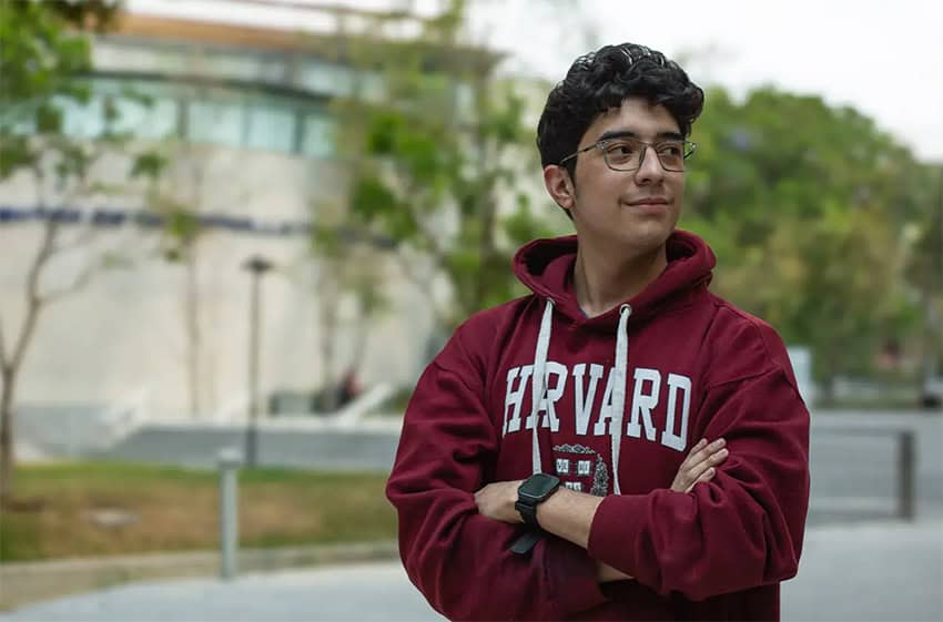 A young Mexican student wears a harvard sweatshirt