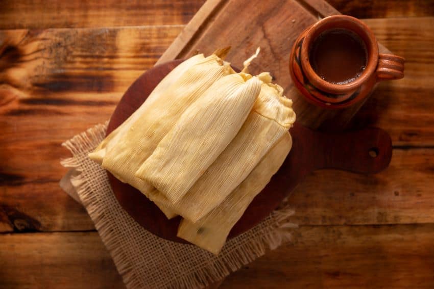 Tamales sirvió en un plato con (posiblemente) Champurrado.