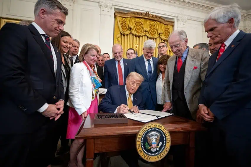 Trump signs a bill surrounded by supporters