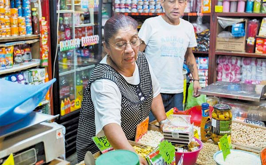 A woman attends to customers at a small Mexican corner store