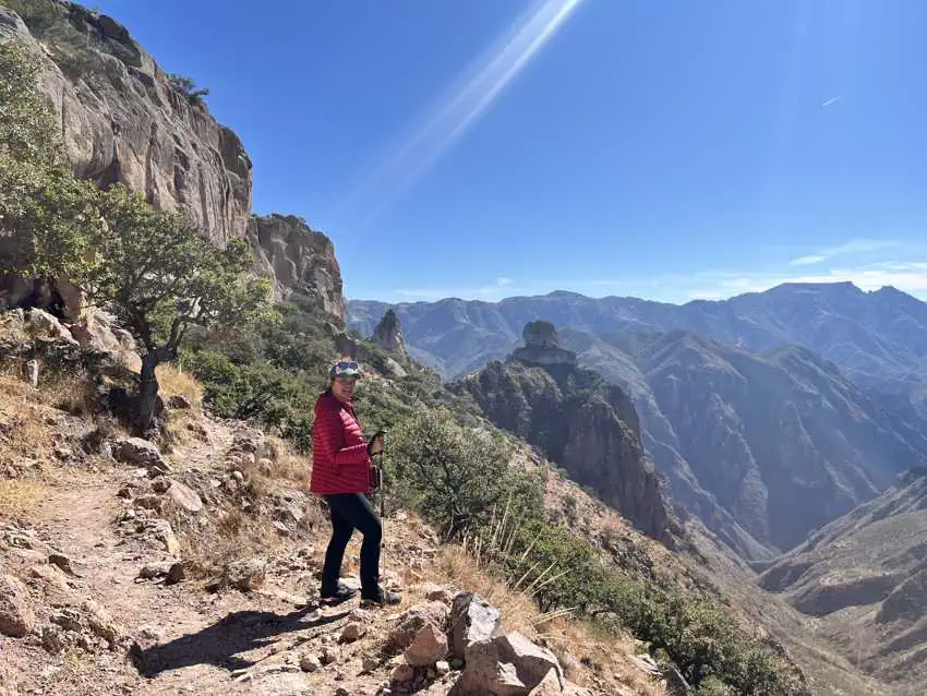 Un excursionista con una chaqueta roja se encuentra en un sendero con vistas al vasto y montañoso cañón de cobre en Chihuahua, México