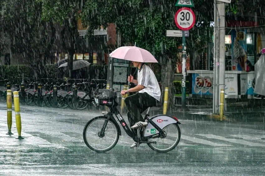 Un hombre con un paraguas monta una bicicleta bajo la lluvia en la ciudad de México