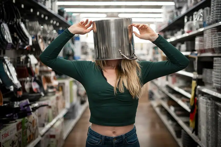A woman with a pan on her head standing in a supermaret aisle