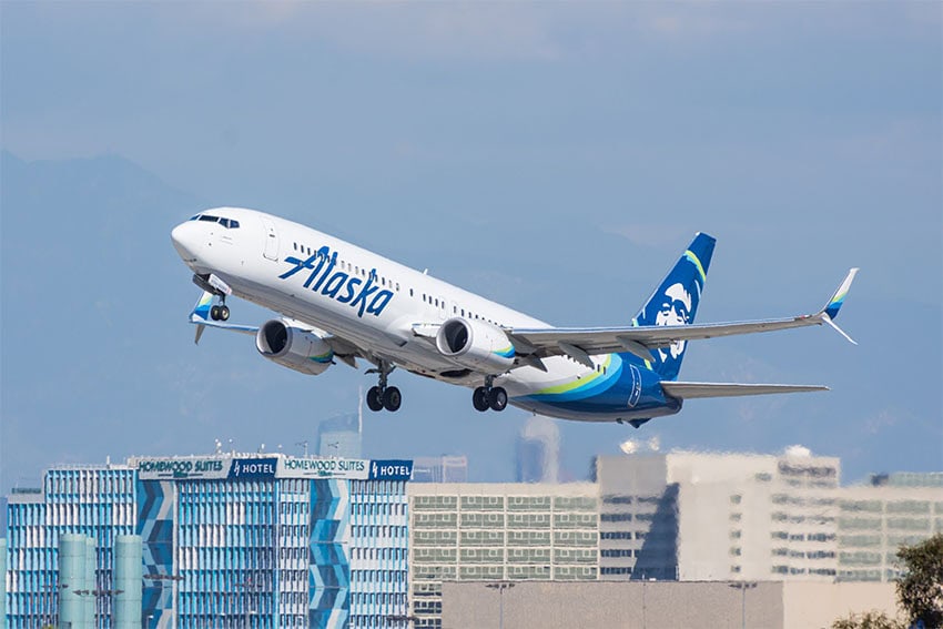 Un avión de Alaska Airlines despegando del horizonte de la ciudad de Los Ángeles