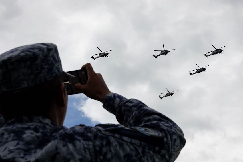 A soldier records the passage of Armed Forces helicopters during rehearsals for the Military Air Parade marking the 215th anniversary of the start of the Mexican War of Independence