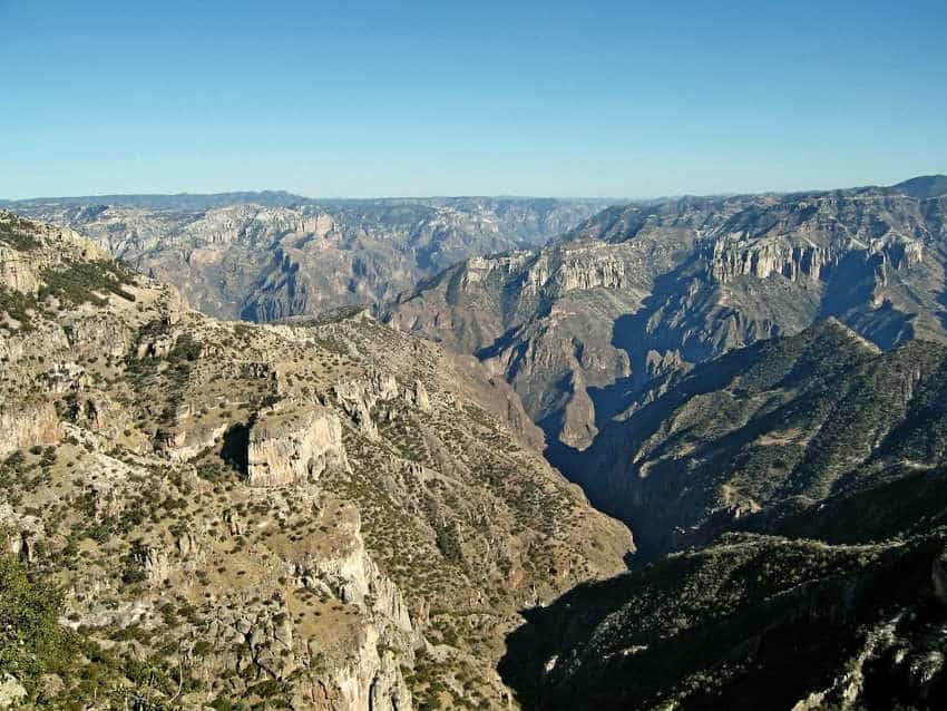 Una vista panorámica del cañón de cobre de México en Chihuahua. El resistente sistema de cañones se extiende debajo de un cielo azul claro, que muestra gargantas profundas y mesas rocosas cubiertas de matorrales.