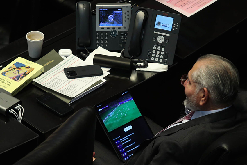 El senador Adán Augusto López mira un juego de fútbol en una tableta durante una sesión del Senado