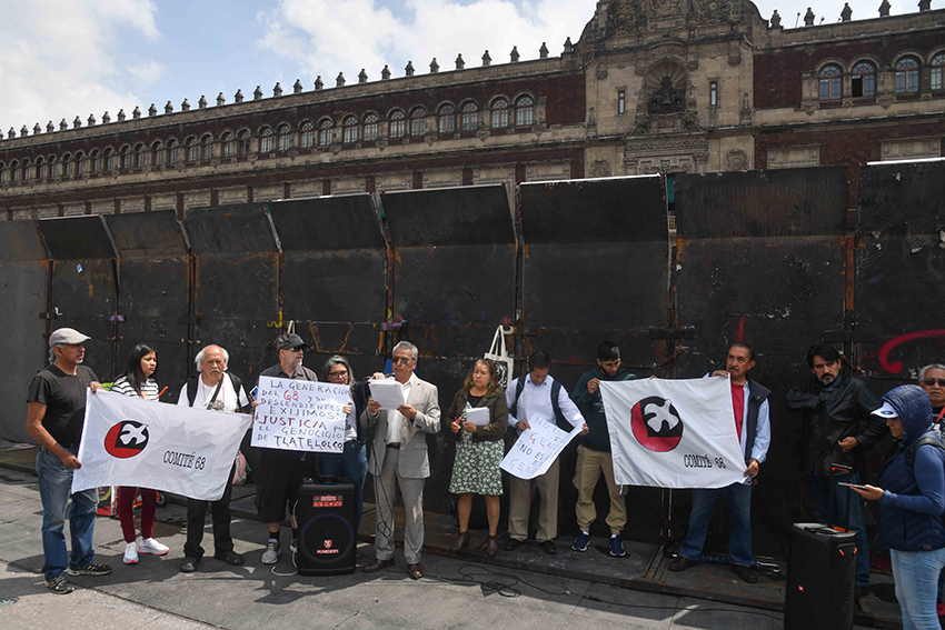 La gente tiene letreros y pancartas frente al Palacio Nacional, que está rodeado de barricadas de metal