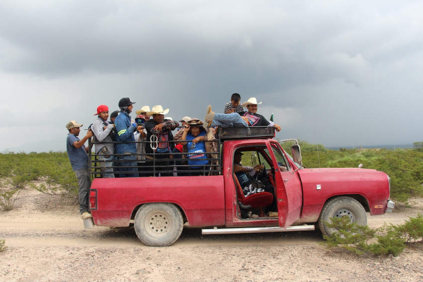 Miembros y simpatizantes del ejido viajando en la parte trasera de una camioneta roja, viajando por caminos de tierra alrededor de Las Margaritas, San Luis Potosí, México.