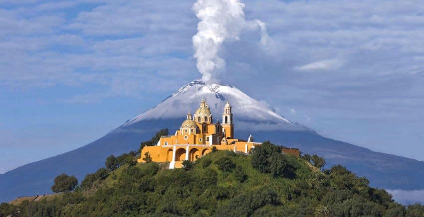 Iglesia de Nuestra Señora de los Remedios en Cholula, Puebla, con el volcán Popocatépetl humeando detrás