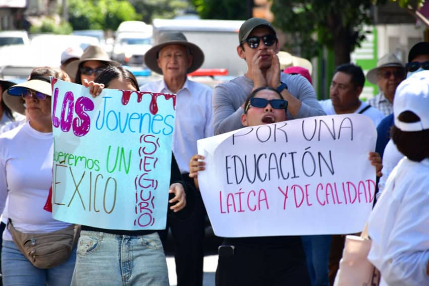 Manifestantes en Chilpancingo, México, sostienen carteles que dicen "Los jóvenes quieren un México seguro" y "Por una educación laica y de calidad" durante una protesta política.