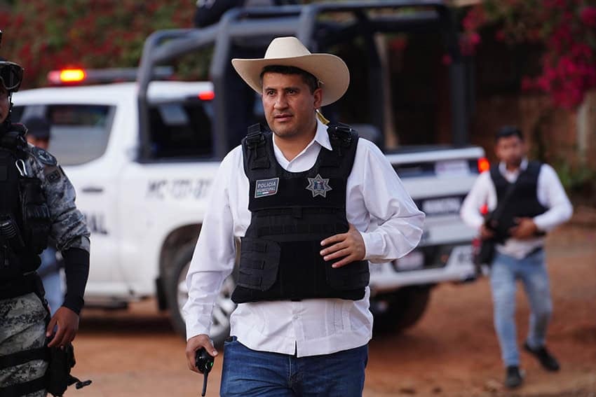 El alcalde de Uruapan, Carlos Manzo, frente a un patrullero con sombrero de vaquero y chaleco antibalas.