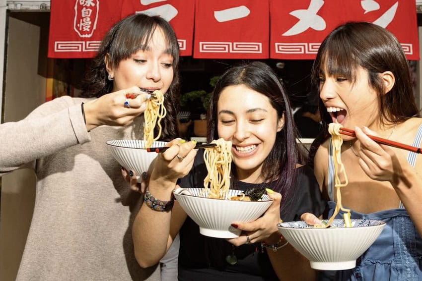 Three women eating noodles
