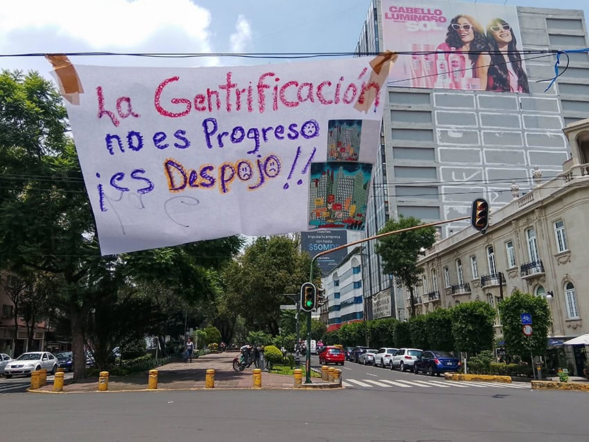 Una pancarta que dice "La Gentrificación no es progreso, es despojo" cuelga sobre una calle de la Ciudad de México.