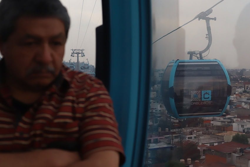 A man looks out over Mexico City from a public transport gondola