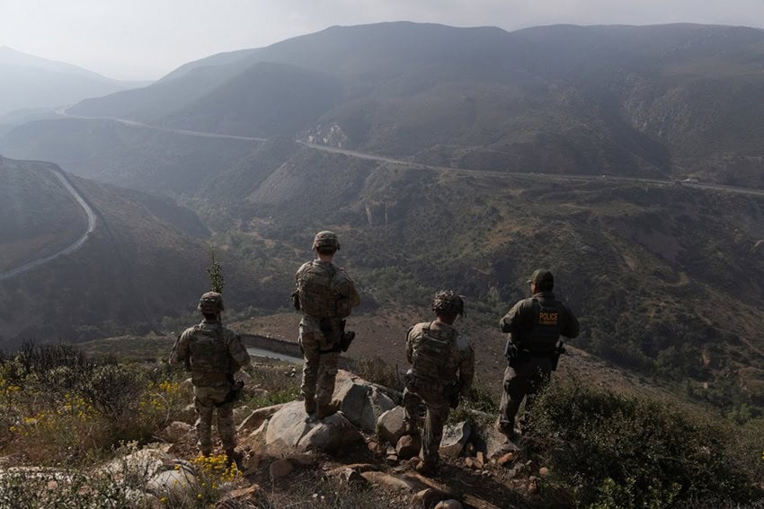 US soldiers look out over an arid valley