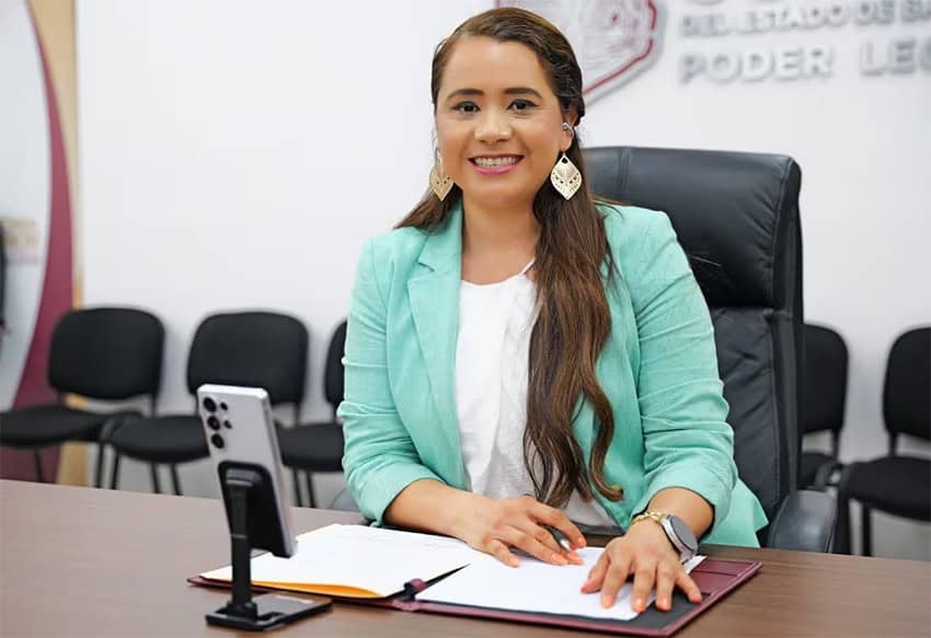 Una mujer con una chaqueta verde menta sentada en una mesa