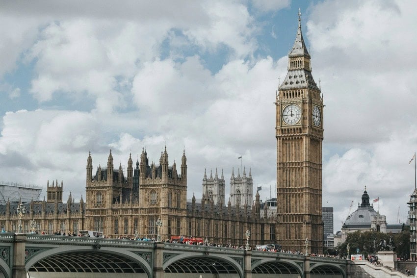 Foto del Big Ben y el Puente de Londres y parte del horizonte de la ciudad contra un cielo azul parcialmente nublado.
