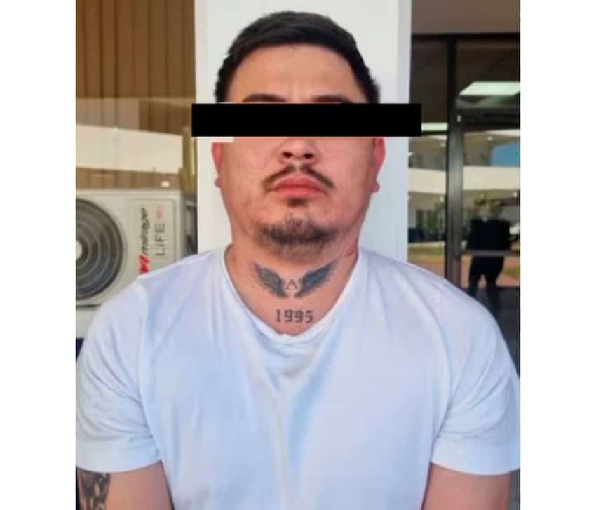 Una fotografía policial de un hombre con una camiseta blanca y los ojos cubiertos por una barra negra.