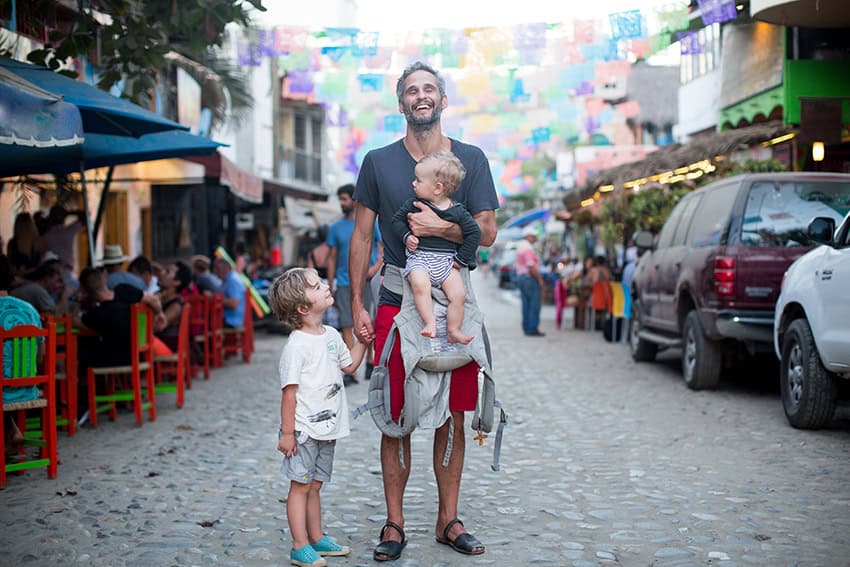 A man holds a baby and a child