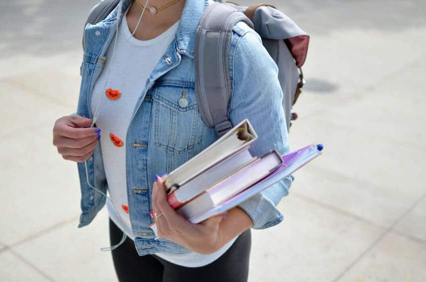 Estudiante universitaria llevando libros y un backback