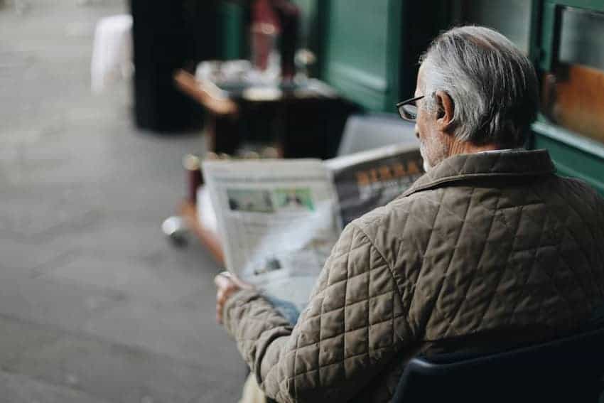 Hombre leyendo un periódico en una cafetería