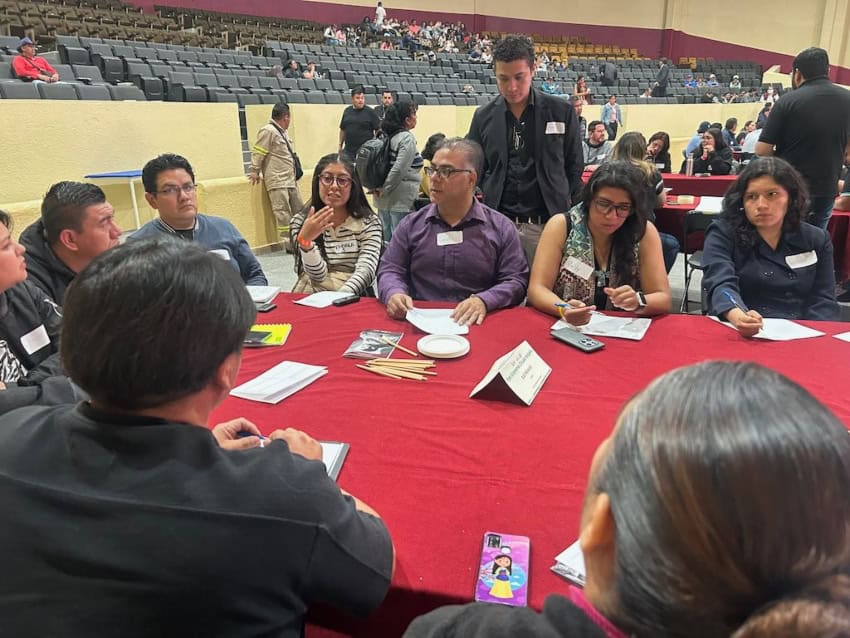 Participantes sentados alrededor de una mesa en una conferencia sobre reciclaje en Ciudad de México.