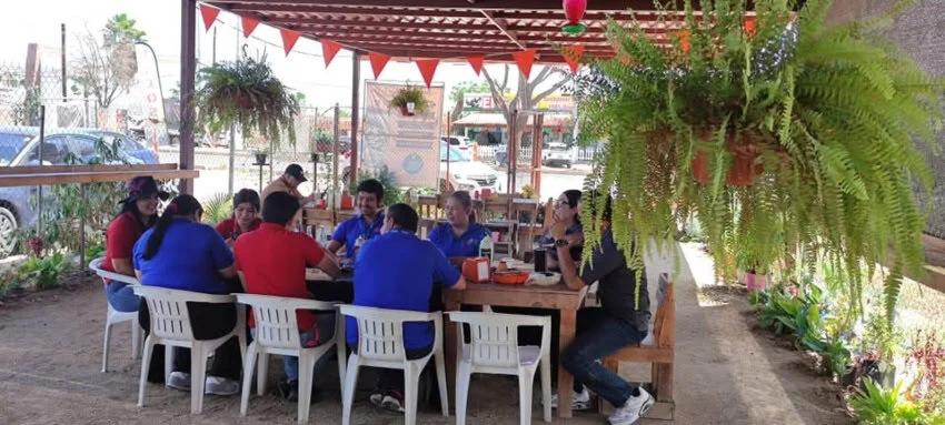 Taquería en México con invitados sentados en sillas de plástico blanco.