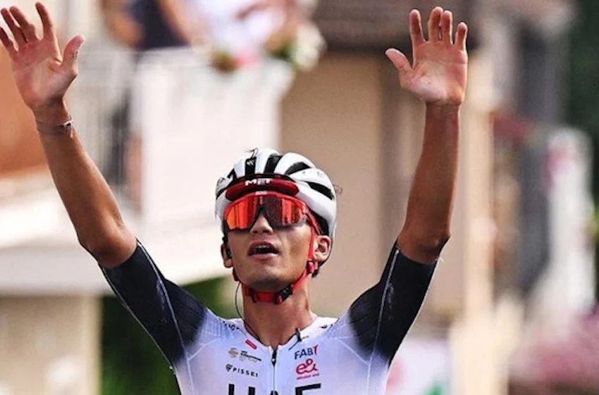 Isaac del Toro levanta las manos en el aire para celebrar haber ganado una carrera